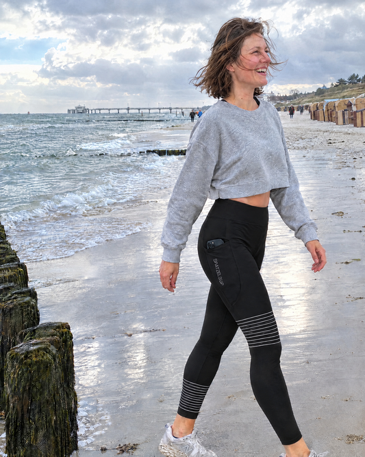 Schwarze SUP-Baltic Sea Leggings mit weißen Streifen an Knie und Wade und Seitentaschen, getragen beim Spaziergang am Ostseestrand