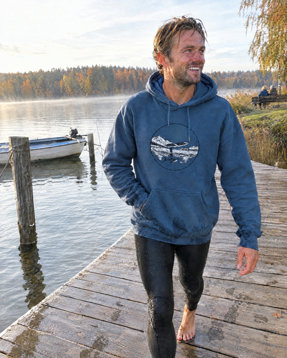 Pump. Glide. Fly. Hoodie in Indigoblau mit Brustprint, getragen auf einem Holzsteg am See nach dem Pumpfoilen