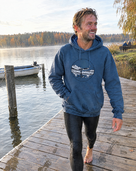 Pump. Glide. Fly. Hoodie in Indigoblau mit Brustprint, getragen auf einem Holzsteg am See nach dem Pumpfoilen